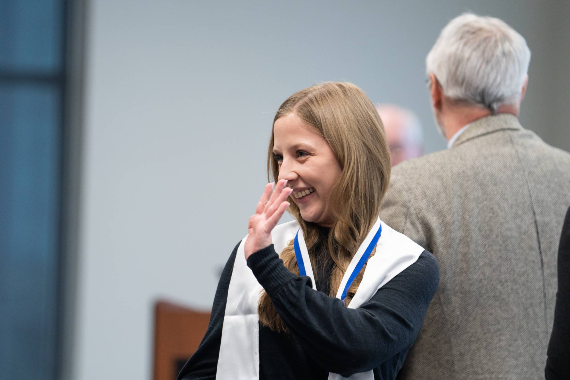 Honors graduate waving to family and supporters.